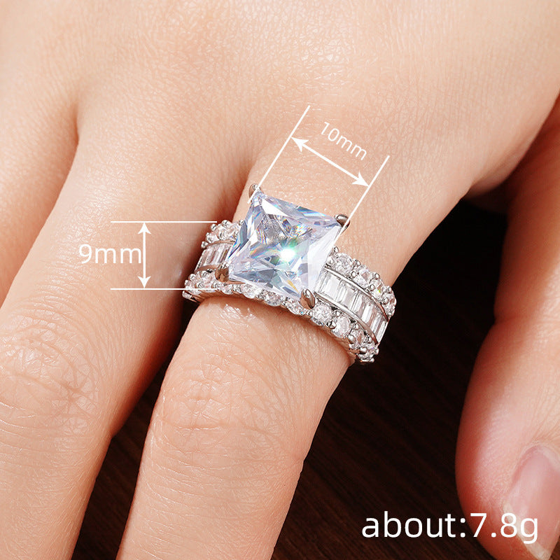 Zircon-inlaid geometric ring on finger with rectangular center stone and stacked pave bands