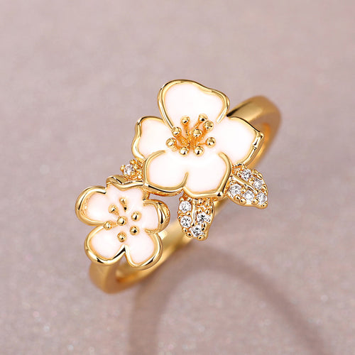 Gold floral ring with three white enamel blossoms and clear crystal settings