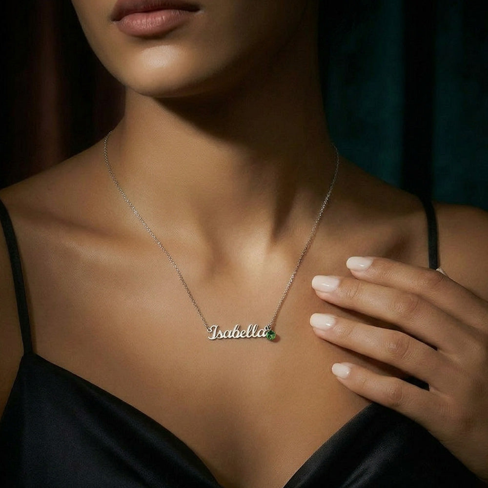 Silver name necklace with Isabela pendant and green round birthstone worn on neckline