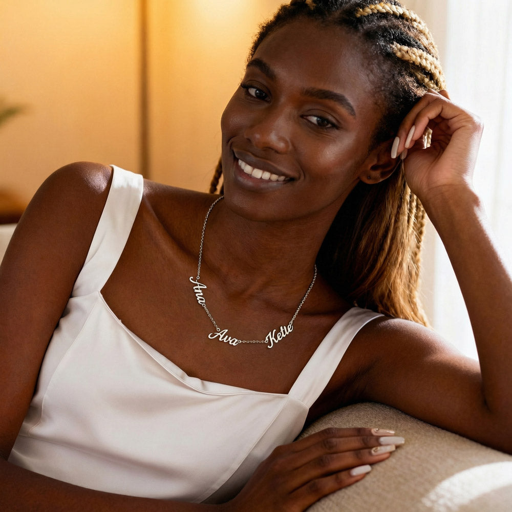 Silver-tone three-name necklace with script charms worn on a white dress neckline