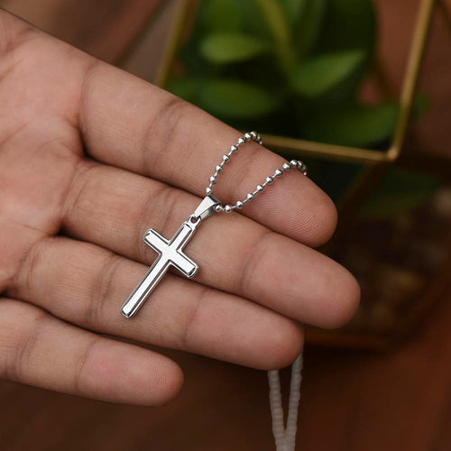 Silver cross pendant necklace with ball chain on a hand