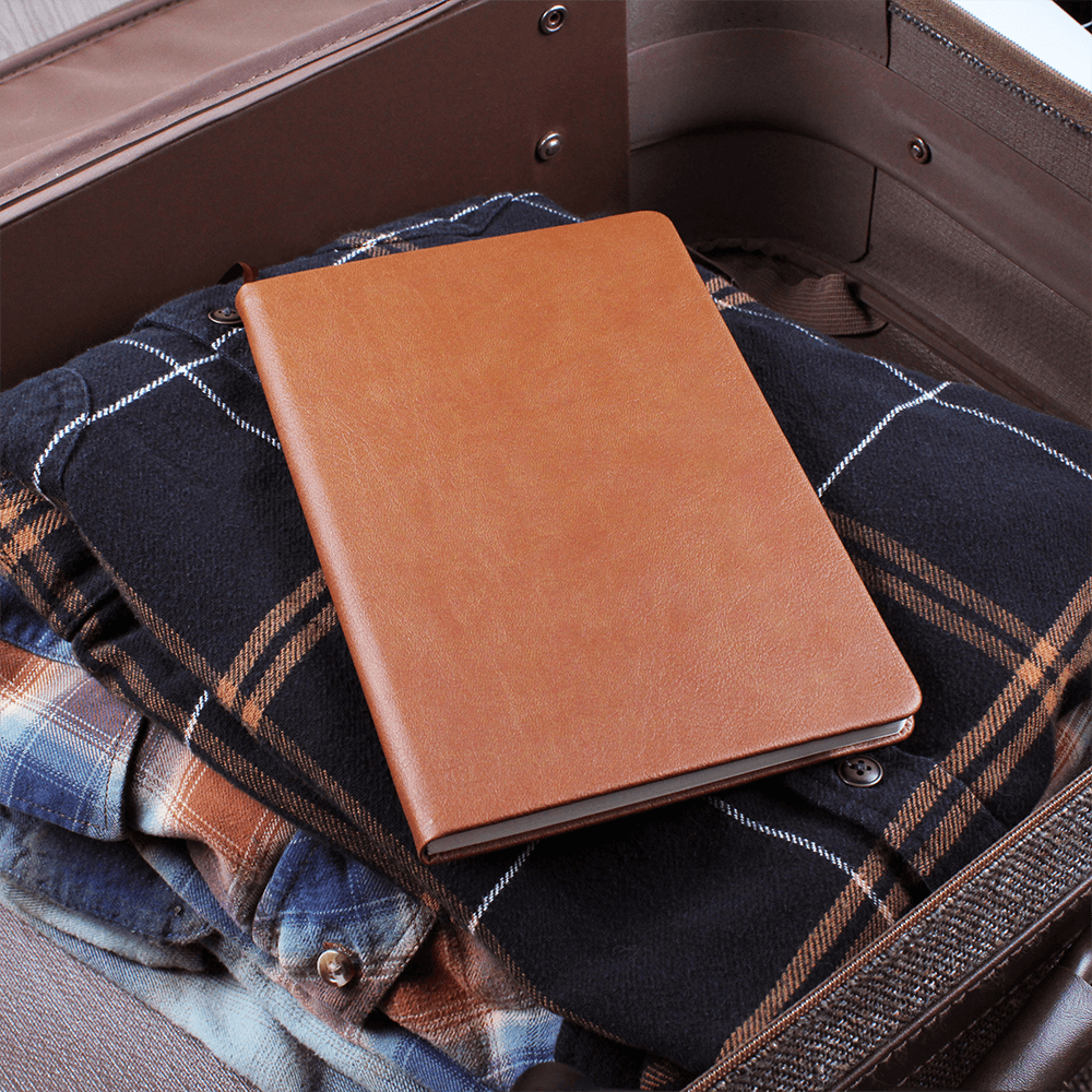 Orange journal on plaid fabric inside a bag, elastic band visible