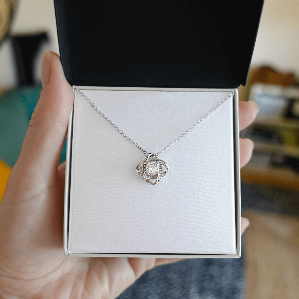 Love knot pendant necklace with round clear stone on silver chain, shown in box