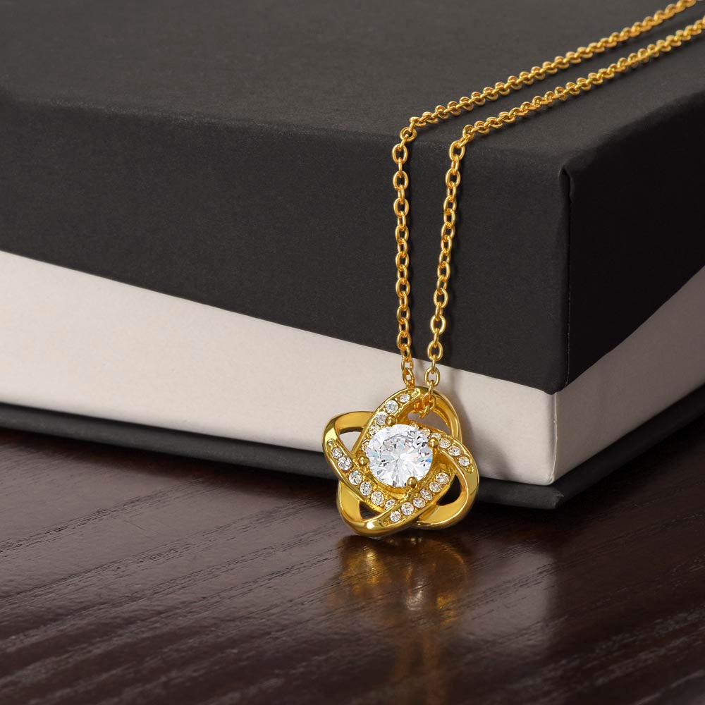 Gold love-knot pendant necklace with round clear center stone and diamond accents