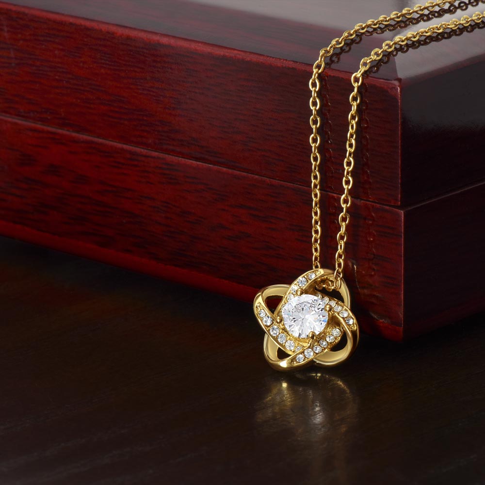 Gold love-knot pendant necklace with round clear center gemstone and diamond accents
