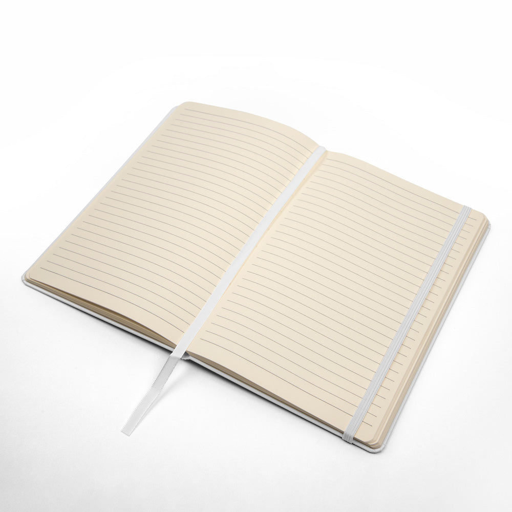 Open white hardcover journal with cream lined pages and light ribbon elastic strap