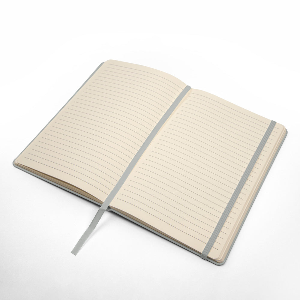 Open silver hardcover journal with cream lined pages and light ribbon elastic strap