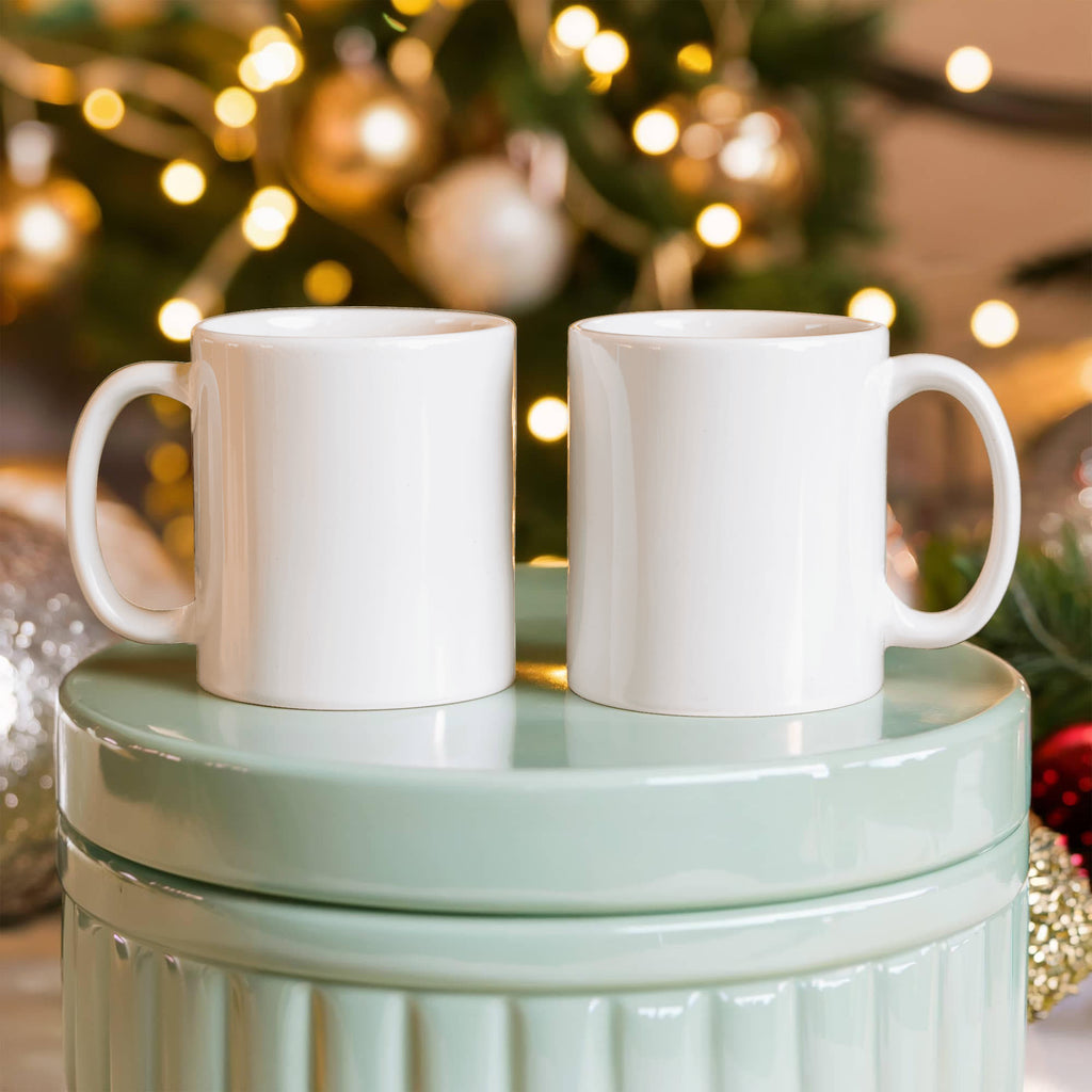 Two white ceramic mugs with curved handles, set together for display
