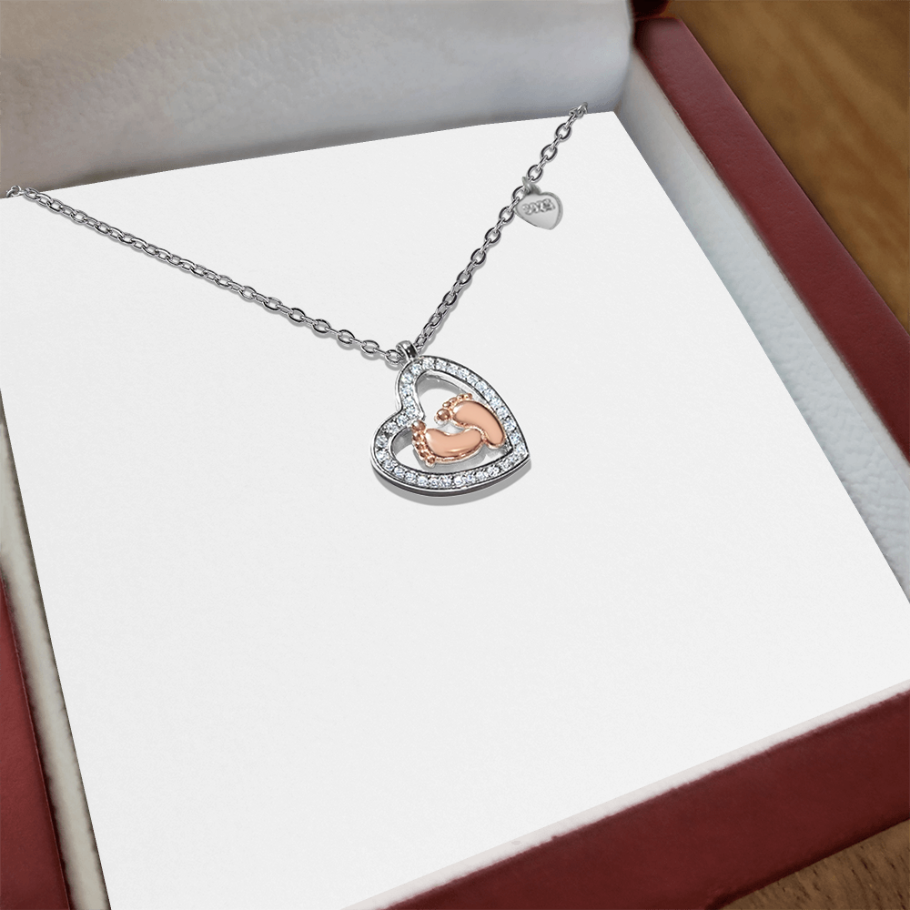 Silver heart pendant necklace with baby feet design and halo of stones