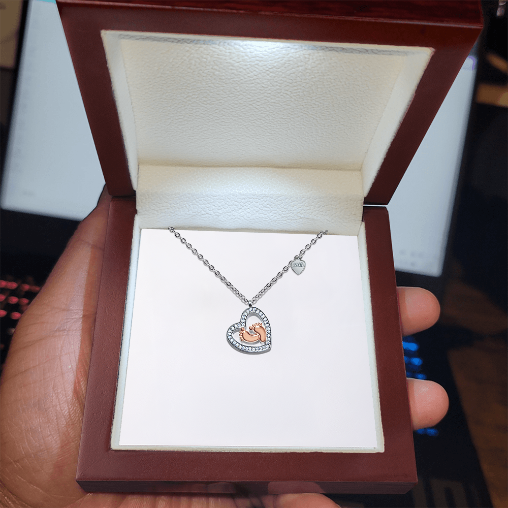 Silver heart pendant necklace featuring baby feet charm on a fine chain