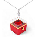 Silver-tone pendant necklace over red rotating rose gift box with gold trim