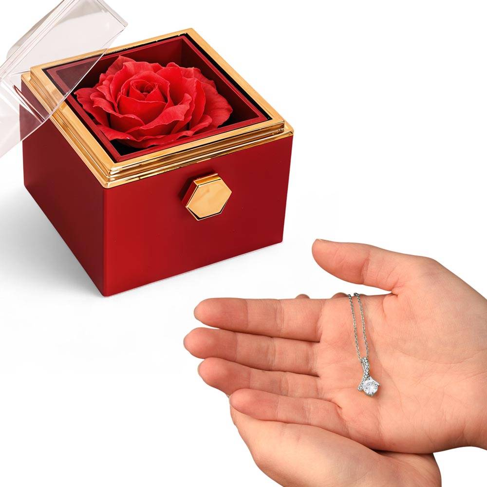 Open red rotating rose gift box with gold edge and silver-tone pendant necklace