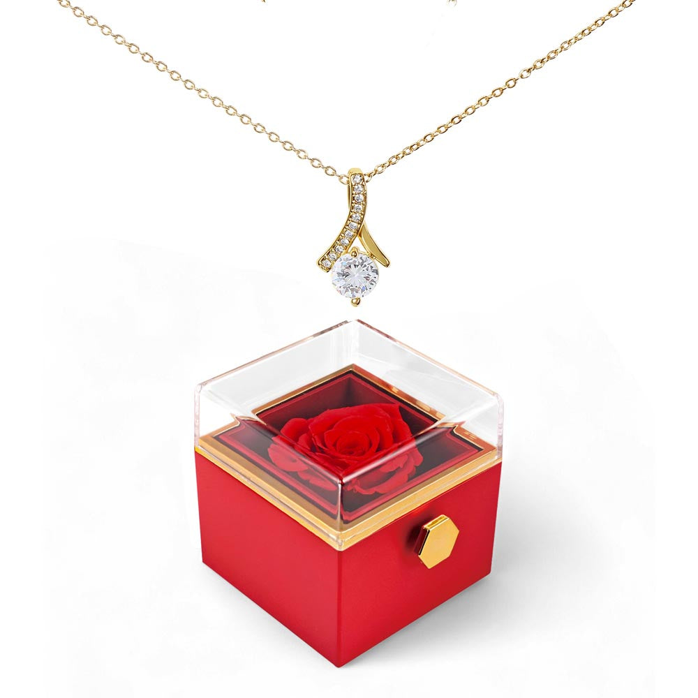 Gold-tone pendant necklace over red rotating rose gift box with clear lid