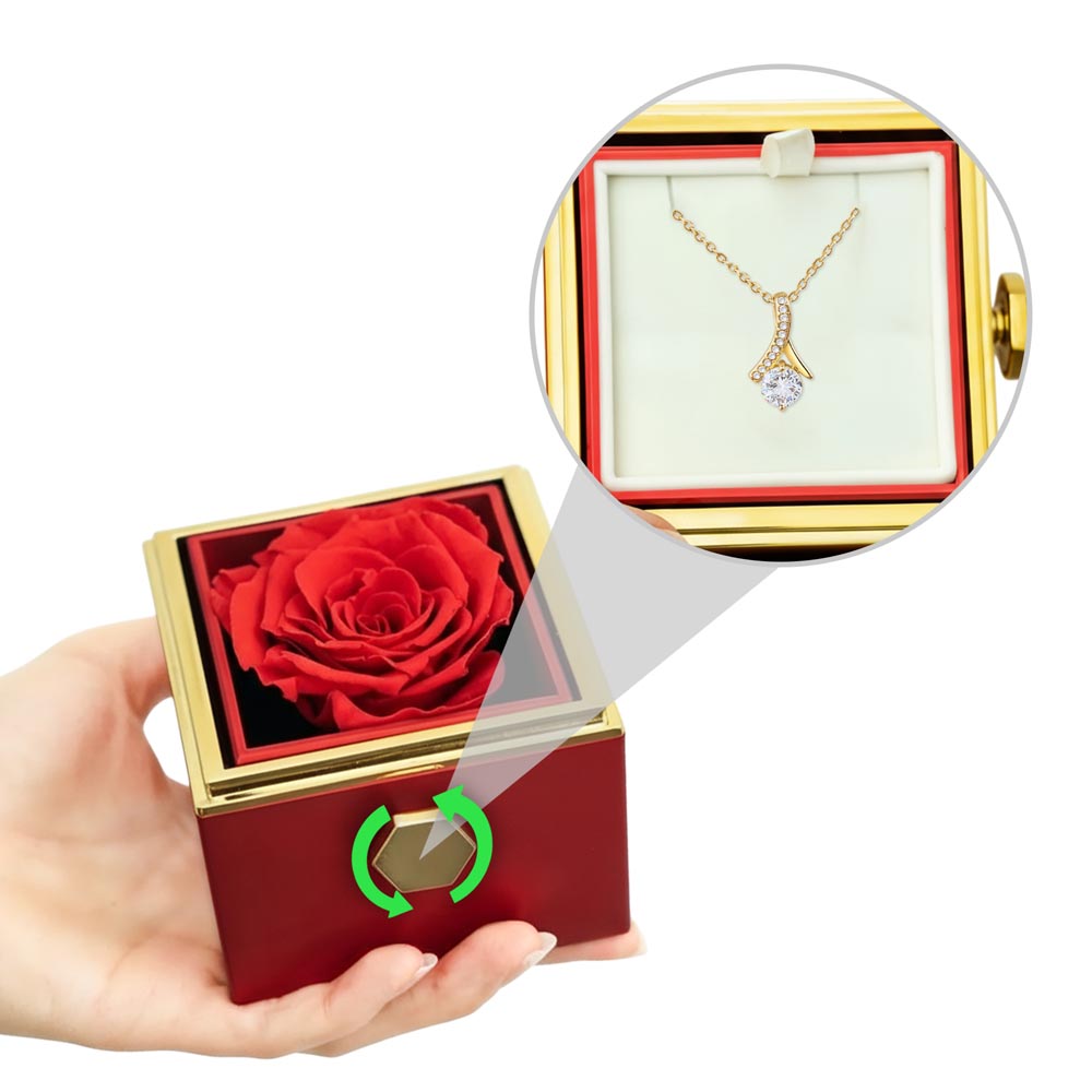 Red rotating rose gift box in hands with gold-tone pendant necklace close-up