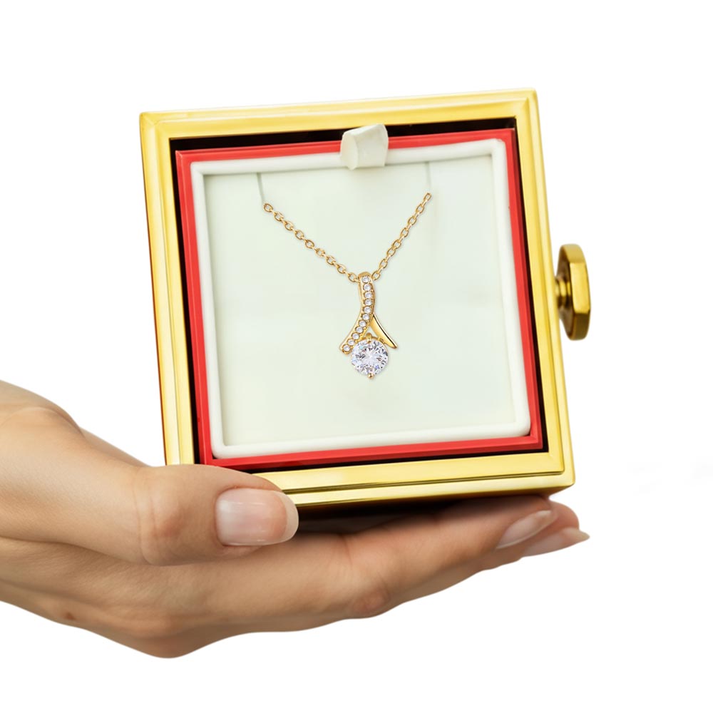 Gold-trimmed red gift box open with gold-tone pendant necklace on white insert