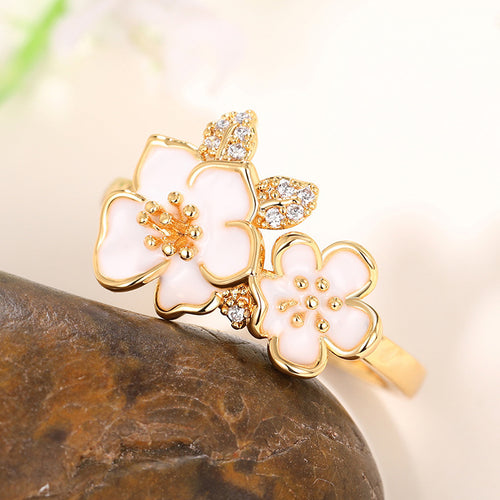Gold floral ring with two white enamel blossoms and clear crystal settings